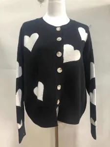Detailed view of women's black knit cardigan with white heart jacquard patterns