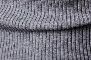 Dettaglio macro della trama del tessuto a maglia a coste grigie su un maglione a collo alto da uomo