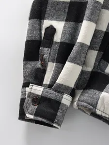 Detail view of men's black and white plaid shirt cuff showing warm fleece lining
