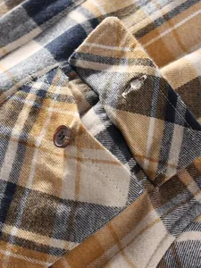 Macro detail of yellow and navy plaid shirt showing collar stitching and button texture.