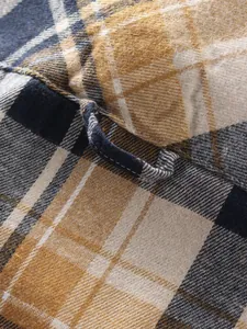 Close-up of a warm plaid flannel shirt fabric showing texture and a hanging loop detail.