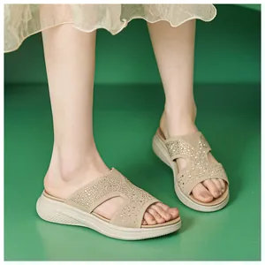 Modische beige Flyknit-Plateausandalen mit funkelndem Strassbesatz, am Fuß getragen.
