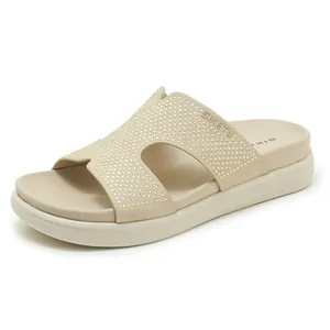 Detalle de sandalia beige con tira en H y adornos de pedrería brillantes
