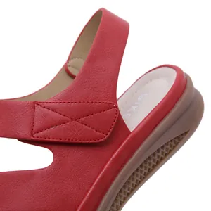 Detailed close-up of a red leather wedge sandal with intricate stitching and sole texture