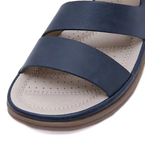 Detail view of navy blue faux leather strap sandal with beige perforated footbed.