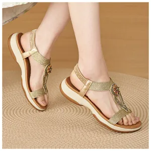 Detailed shot of gold Bohemian sandals with rhinestone flower decoration on woven rug
