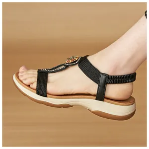 Detail view of Bohemian flat sandals with black elastic straps and rhinestones.