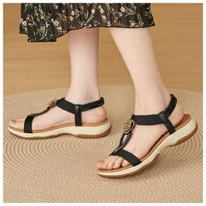 Detailed view of women's black Bohemian sandals with rhinestone flower on woven mat