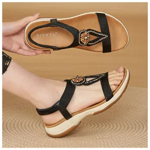 Close-up detail of bohemian rhinestone sandals with braided straps and soft sole