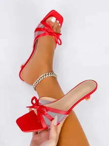 Elegantes sandalias rojas de punta abierta con lazos de satén y detalles de malla, tacón bajo.