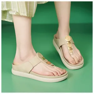 Primo piano di eleganti sandali infradito beige con plateau e dettagli dorati