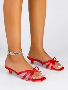 Elegantes mules rojos de tacón bajo con lazo y detalles de malla en los pies