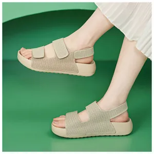 Vista detallada de sandalias tejidas beige con correas de velcro sobre fondo verde