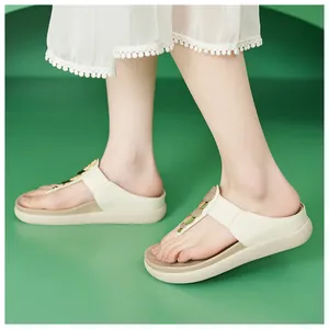 Dettaglio di infradito con zeppa color bianco sporco con strass indossati da una modella.