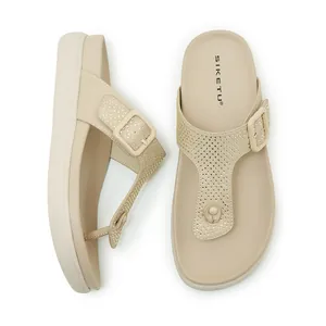 Dettaglio dei sandali beige con zeppa, infradito con strass e cinturino con fibbia