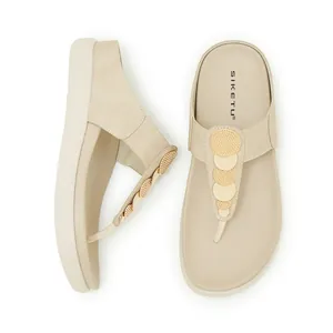 Vista dall'alto di infradito beige con zeppa ed eleganti inserti circolari dorati.