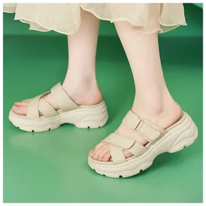 Detailansicht von beigen Plateausandalen mit verstellbarem Klettverschluss auf grün