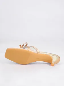 Vista de la suela de elegante mule color champán con tacón de gatito y detalle de lazo.