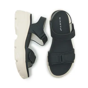Close-up of black platform sandals with adjustable velcro straps and thick white soles.