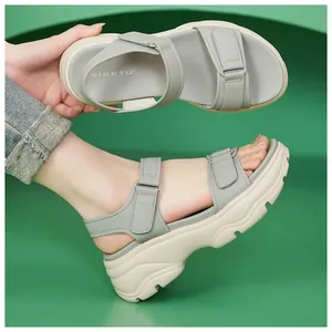 Close-up view of grey chunky platform sandals with velcro straps worn by a model.