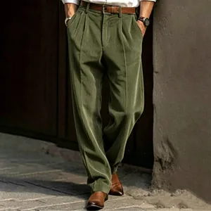Close-up detail of men's green corduroy straight-leg trousers with pleated waist.
