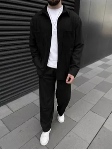 Detailed view of a man wearing a black corduroy shirt and matching pants set in street