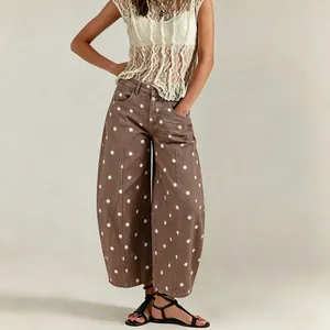 Detail shot of brown polka dot barrel jeans showing curved leg fit and pattern.