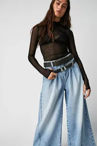 Detail showing light blue wide-leg denim jeans with a pleated waist and vintage wash.