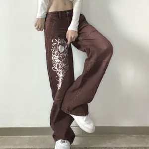 Detail shot of brown wide-leg jeans with silver heart graphic print in streetwear style.