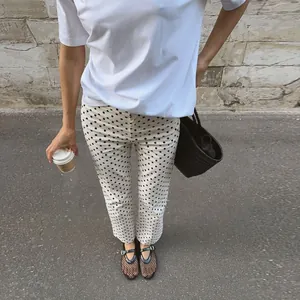 Street style φωτογραφία γυναίκας με λευκό πουά τζιν παντελόνι και μαύρη πλεκτή τσάντα