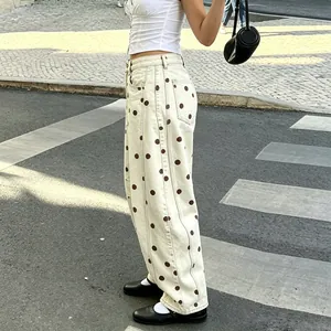 Side view detail of cream polka dot wide-leg curved denim pants on a model