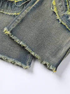 Close-up detail of men's distressed denim jeans with raw tassel hem and vintage wash