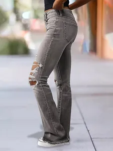 Detail of vintage grey distressed flare jeans with ripped knees and raw hem
