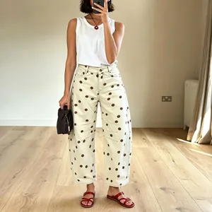 Full view of women's beige low-waist curved leg jeans featuring brown polka dot pattern