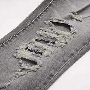 Macro view of distressed ripped details on high-quality grey stretch denim jeans fabric