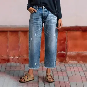 Detailed view of women's straight-leg cropped denim jeans with raw hem and distressed finish