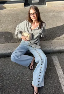 Stylish women's light blue wide-leg jeans with unique side button detailing for street fashion.