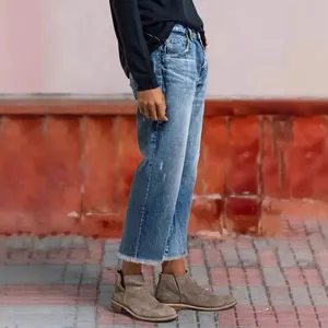 Side detail of women's loose straight-leg cropped jeans with raw hems in light wash denim