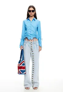 Detailed view of light blue denim jeans featuring a unique multi-button diagonal closure.