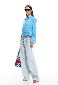 Close-up view of light blue wide-leg jeans with a unique multi-button front seam.
