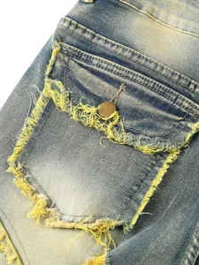 Macro view of yellow fringe distressed denim pocket detail on blue jeans.