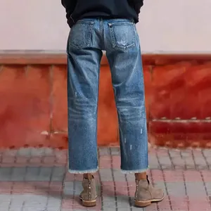 Back view of women's blue straight-leg cropped jeans with raw fringed hem details