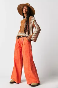 Full detail view of vibrant orange wide-leg denim jeans styled on a female model