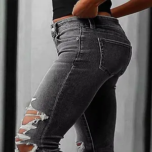 Detail view of grey ripped skinny jeans showing distressed holes on the thigh and hip area