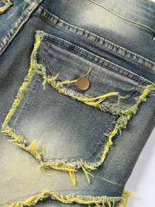 Detailed view of vintage washed denim pocket featuring heavy distressing and yellow fringe