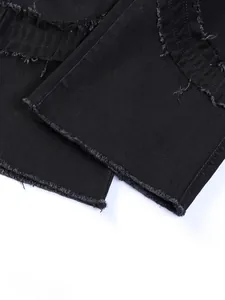 Macro detail of frayed tassels and distressed raw edge hem on black denim flared jeans