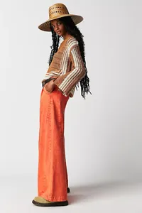 Professional side view detail of orange high-waisted wide-leg denim pants on model