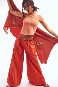 Detailed macro shot of bright orange wide-leg denim jeans featuring high-waist vintage styling