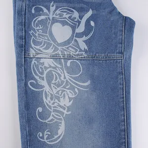 Close-up detail of white heart and ornate flourish graphic print on blue denim jeans fabric