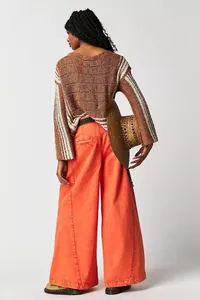 Back view of stylish orange wide-leg jeans paired with a striped knit sweater and hat